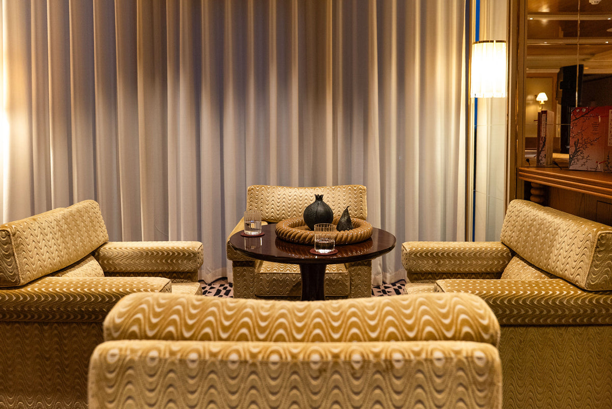 Luxurious living room-style area with patterned armchairs and a round wooden coffee table.