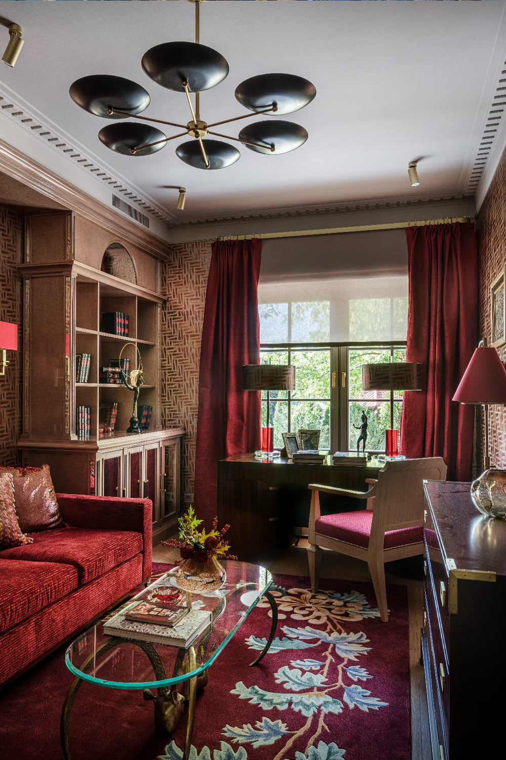 Luxurious living room with red upholstered sofa, glass coffee table with copper legs, and red curtains.
