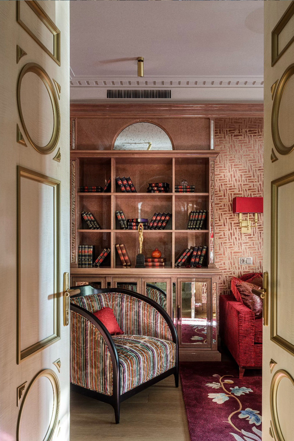 Decorative interior with a bookshelf, armchair upholstered in a striped fabric, and red rug.