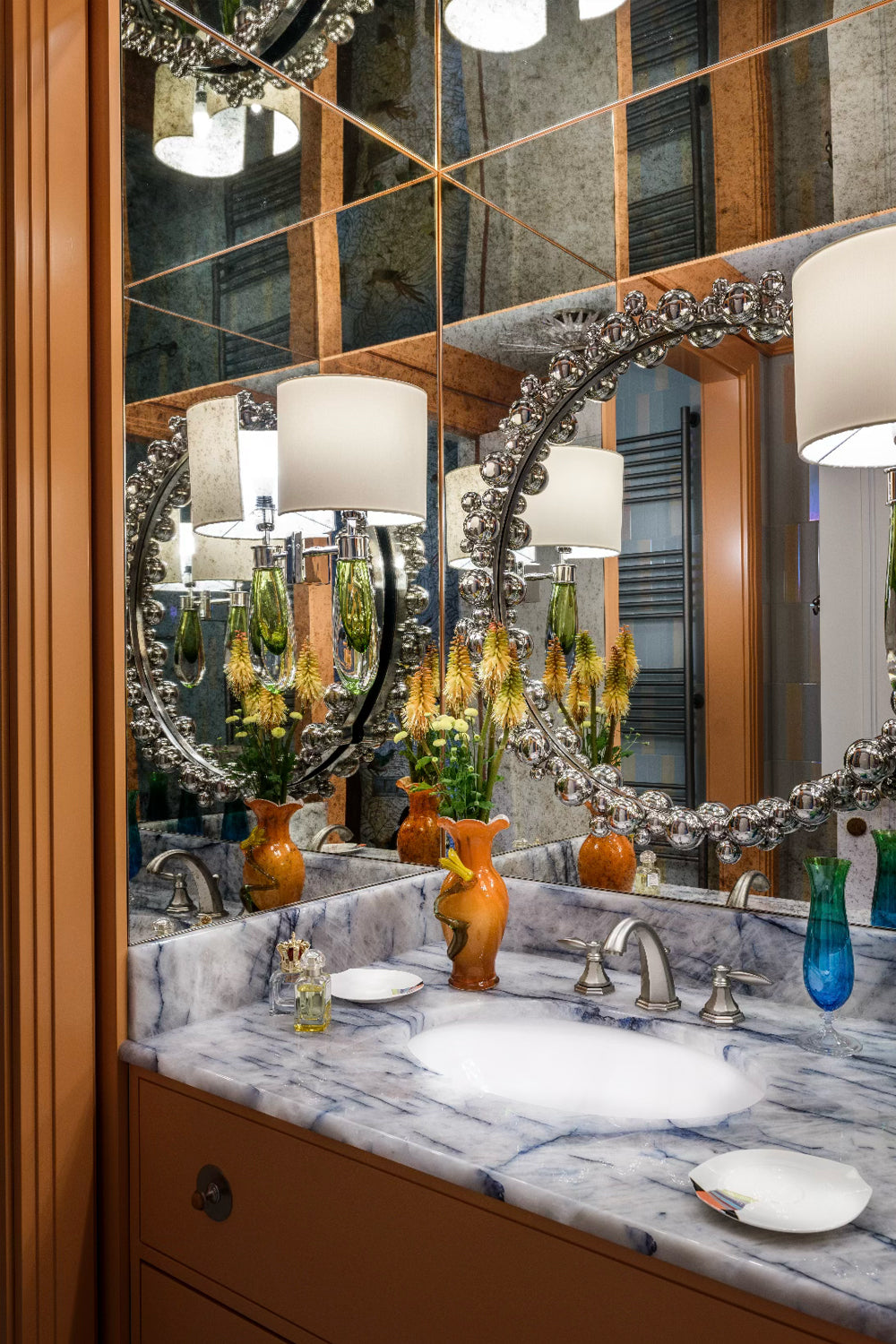 Bathroom vanity with marble countertop, round mirror, and decorative elements.