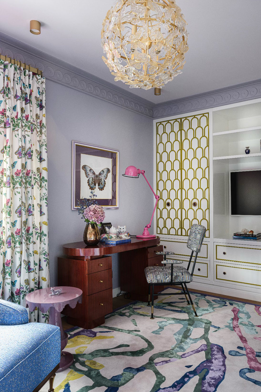 Bedroom with floral curtains, a brown wooden desk and  an upholstered armchair.