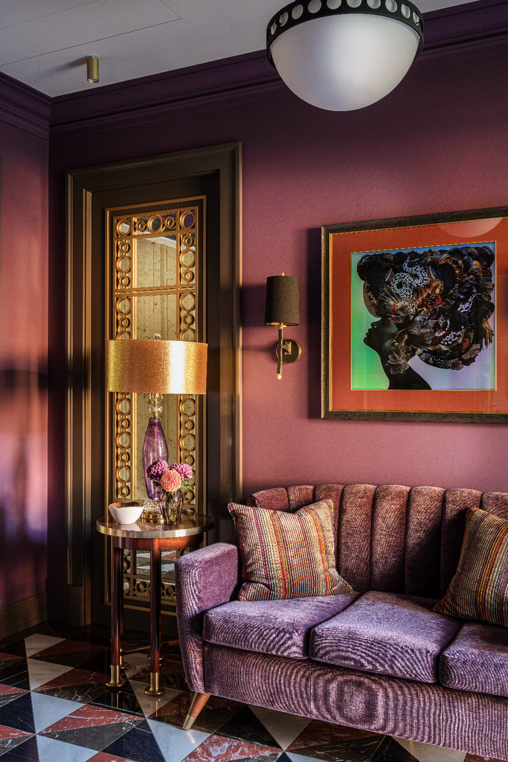 Luxurious interior with a purple sofa, decorative pillows, and a colourful painting on a purple wall.