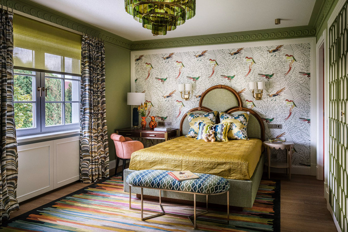 Decorative bedroom with green walls, grey upholstered bed, and brown wooden furniture.