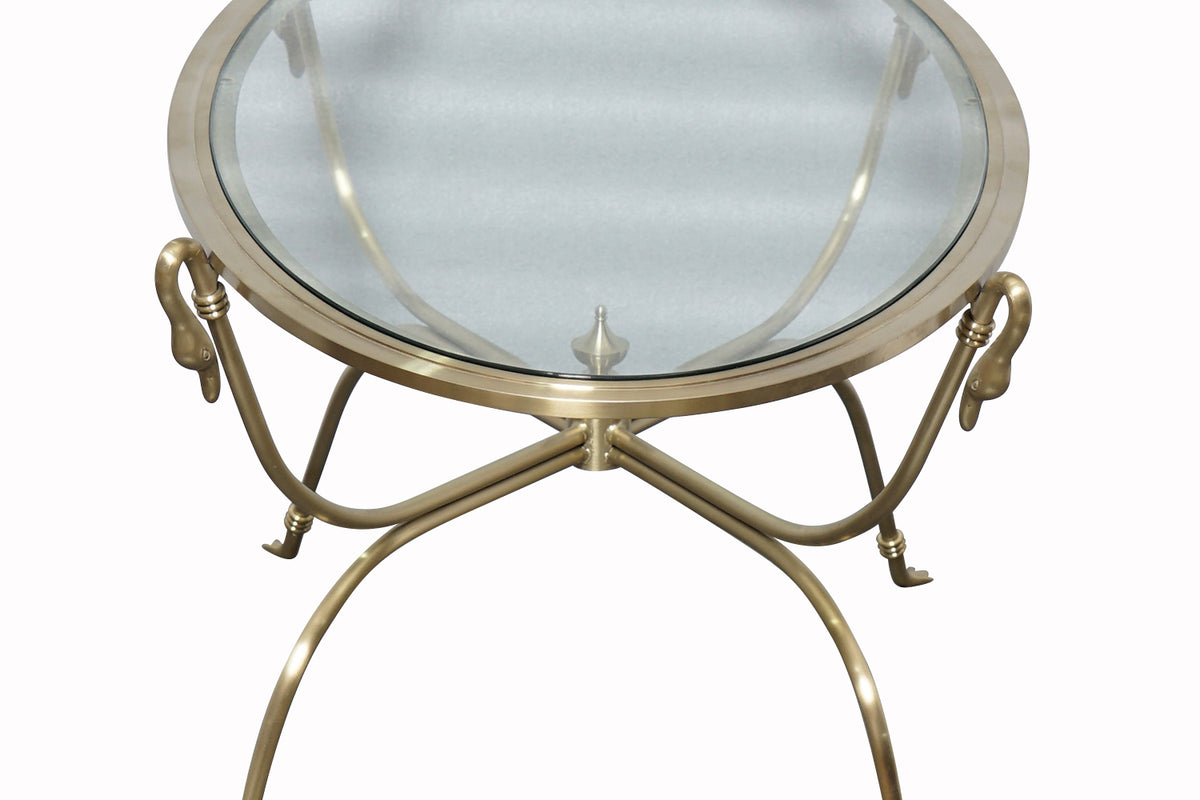 Round glass table with gold metal frame with swan heads, seen from above.